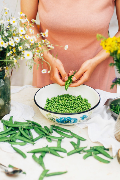 Woman podding fresh peas in the kitchen. Woman podding fresh pea - 写真・画像