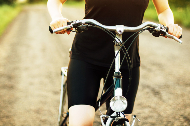 Detalhe de uma bicicleta. Uma mulher a andar de bicicleta. Bicicleta na estrada
  - Foto, Imagem