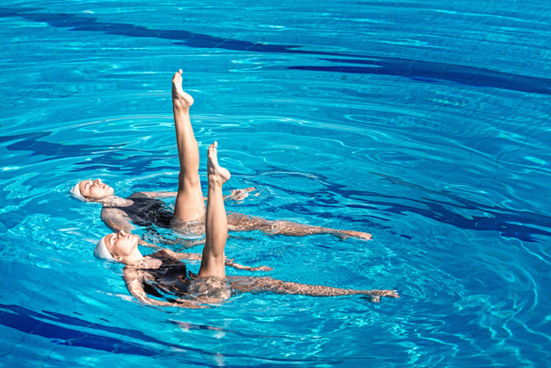 par de natação realizando dança na piscina
 - Foto, Imagem
