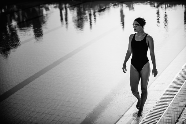 Привлекательная женщина-пловчиха прогуливается у бассейна
 - Фото, изображение