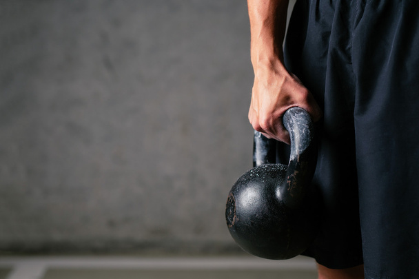athlete holding kettlebell weight - Foto, afbeelding