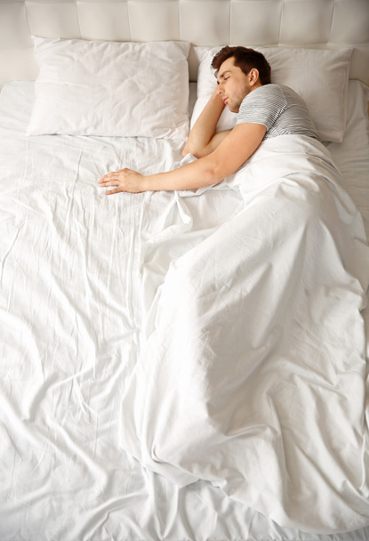 Man sleeping alone in  bed - Foto, afbeelding