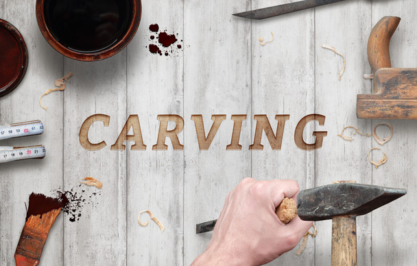 Carving word carved in wood with hammer and chisel. Beside is brush, paint, wood plane, ruler, shavings. - Photo, Image