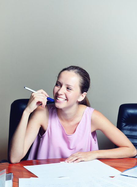Young businesswoman sitting at workplace and reading paper in office - Фото, зображення