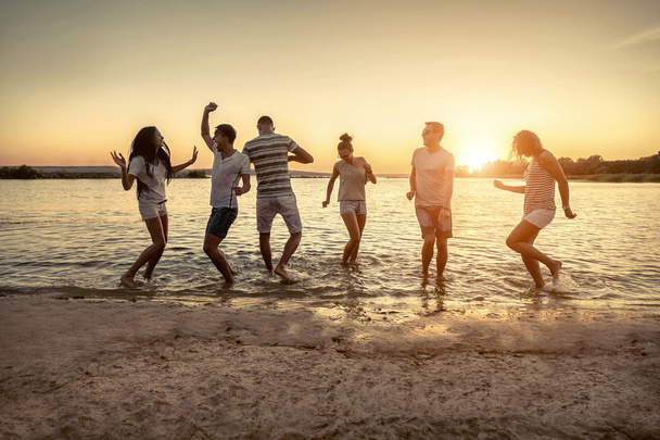 Silueta de grupo de jóvenes en la playa
. - Foto, Imagen