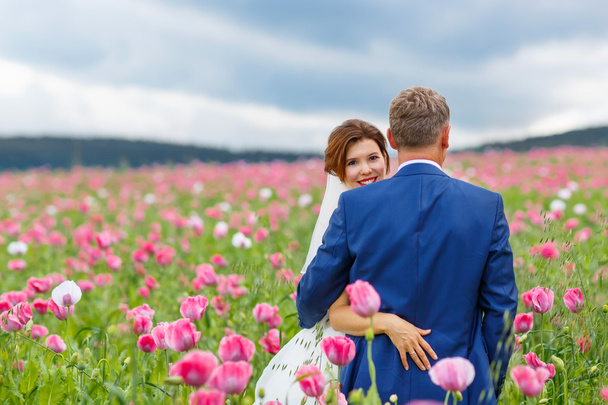 Happy wedding couple in pink poppy field - Photo, Image