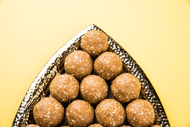 El sésamo indio dulce o tilgul laddu o til gul laddu, compuesto de jaggery y semillas de sésamo, hecho a mano, redondo, dulce indio preparado en el festival Makar Sankranti
 - Foto, imagen