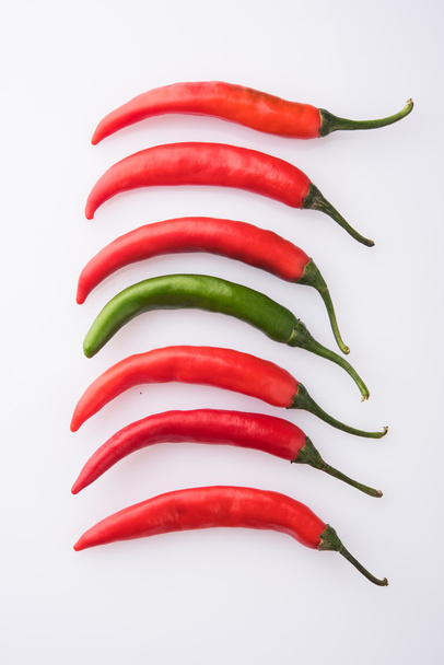 red chilli in line one chilli reverse showing uniqueness concept, original concept, different concept, against stream concept, isolated on red background - Фото, зображення