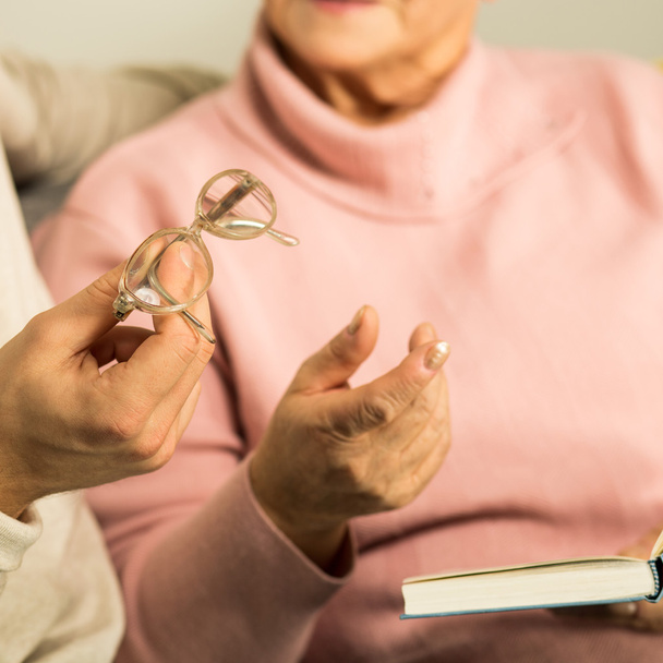 Giving senior woman reading glasses - Foto, afbeelding