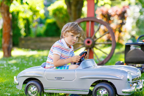 Kid boy dirigindo com grande carro de brinquedo ao ar livre
 - Foto, Imagem