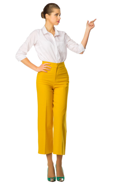 Woman in yellow pants shows pointing gesture - Fotó, kép