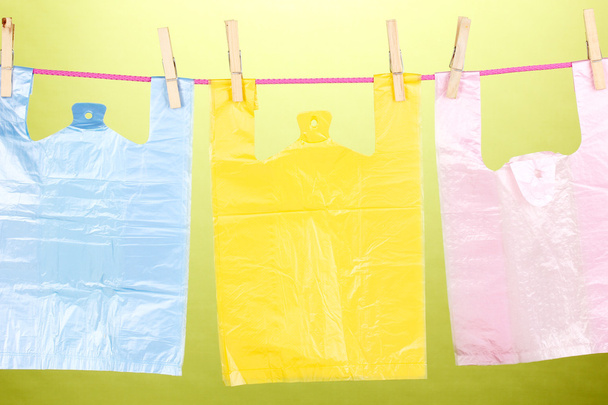Cellophane bags hanging on rope on green background - Foto, afbeelding
