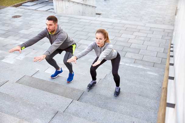 couple doing squats on city stairs - Foto, Imagen