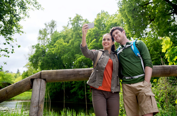 couple with backpacks taking selfie by smartphone - 写真・画像