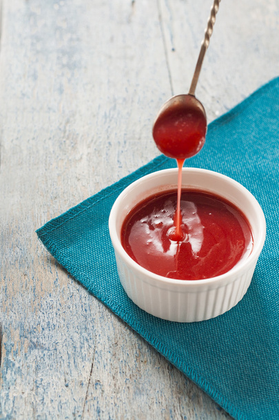 Red sauce dripping from a spoon in the white form - Valokuva, kuva