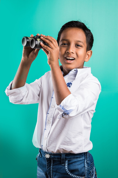 malý indiánský kluk s dalekohledem, malý asijský kluk použítý dalekohled, indiánský chlapec s dalekohledem, zvědavý malý chlapec s dalekohledem, izolovaný na zeleném pozadí - Fotografie, Obrázek