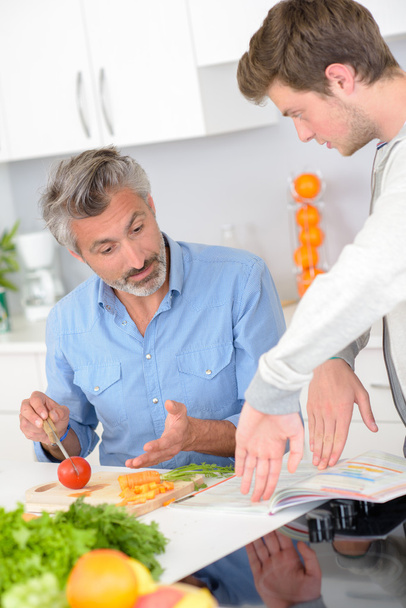 Man preparing meal, hand gestures with younger man - Fotó, kép