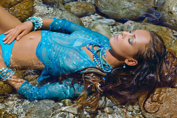 attractive boho woman lying in water on stone beach - Fotografie, Obrázek