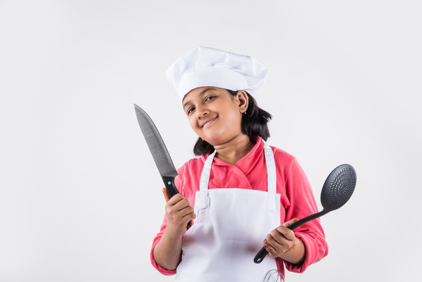 маленькая девочка шеф-повар, маленькая девочка повар, азиатская маленькая девочка в форме шеф-повара, индийская девушка в одежде шеф-повара, кулинария и концепция людей - улыбающаяся маленькая девочка в шляпе повара
 - Фото, изображение