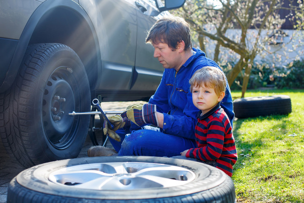 Petit garçon et son père changeant de roue en voiture
 - Photo, image