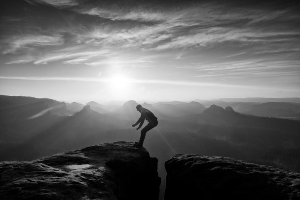 Mann in Schwarz springt zwischen den Gipfeln. verträumter Tagesanbruch - Foto, Bild