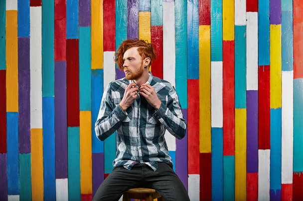young thoughtful redhead bearded man in plaid shirt on colourful - Foto, afbeelding