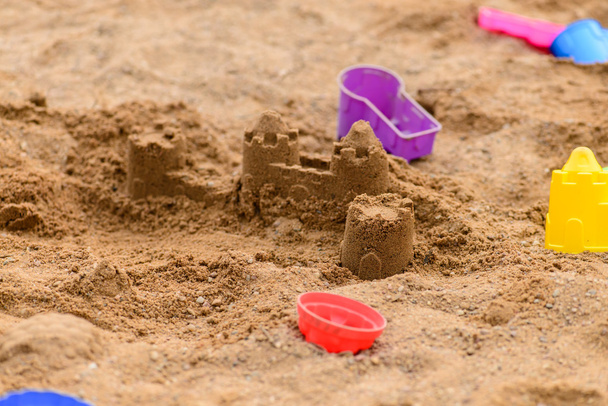 buntes Spielzeug im Sandkasten an einem sonnigen Tag, flache Wassertiefe - Foto, Bild