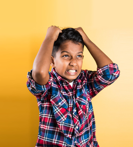 indian kid and headache or cephalalgia, asian kid and headache or cephalalgia, indian kid holding head, indian kid pulling hair in pain and stress, red background, 10 year indian boy - Photo, Image
