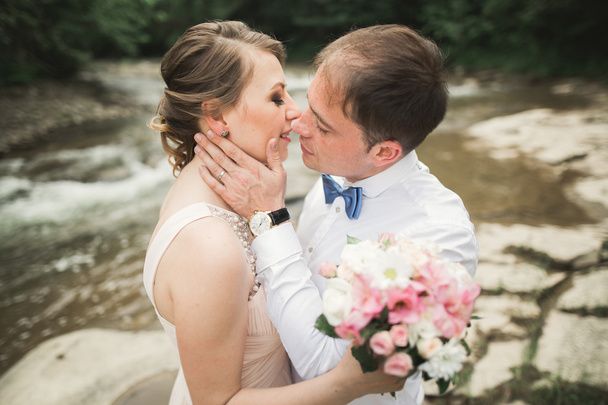 Noiva sorri com os olhos fechados, enquanto o noivo toca seu rosto delicadamente
 - Foto, Imagem