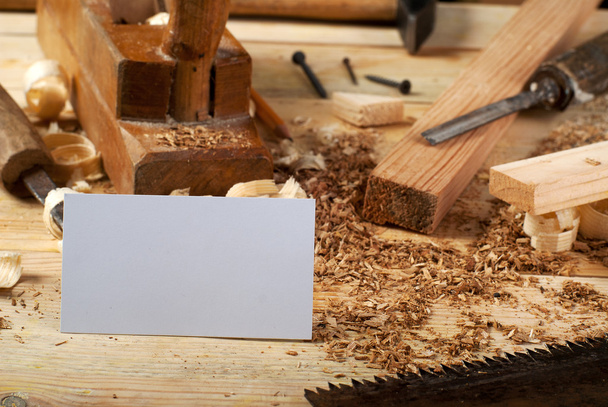 Επαγγελματική κάρτα στο ξύλινο τραπέζι για τα εργαλεία ξυλουργών με πριονίδι. - Φωτογραφία, εικόνα