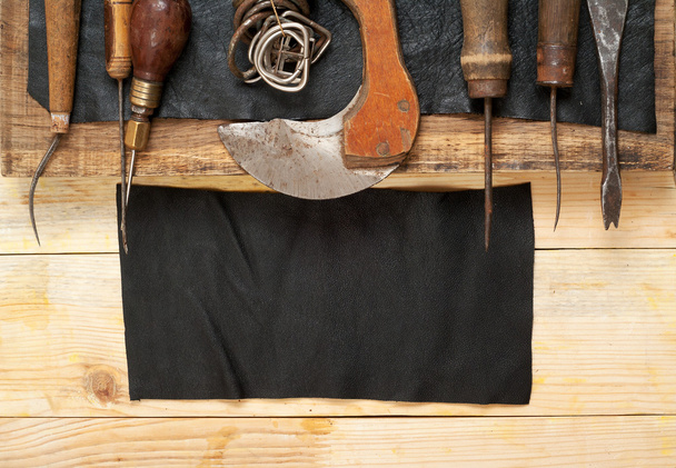 Lederen craft tools op houten achtergrond. Craftmans Bureau. Stukje verbergen en handgemaakte tools. Bovenaanzicht - Foto, afbeelding