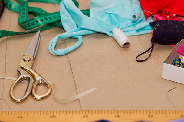 Naaien textiel of doek. De tabel van het werk van een kleermaker. Textiel tools. Schaar reel van draad, tapes en natuurlijke stof te meten. Kopieer ruimte. Bovenaanzicht - Foto, afbeelding