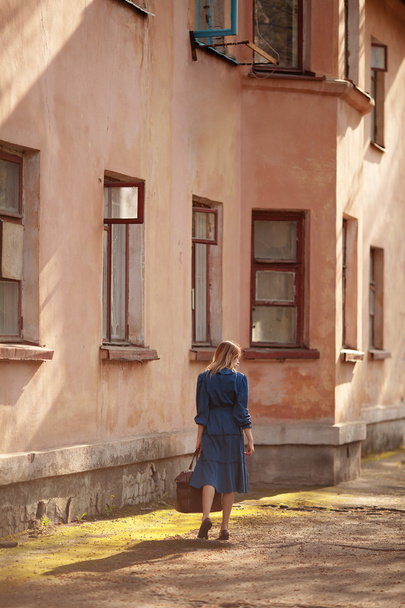 Young traveler in vintage blue dress leaves home for adventures. - Φωτογραφία, εικόνα
