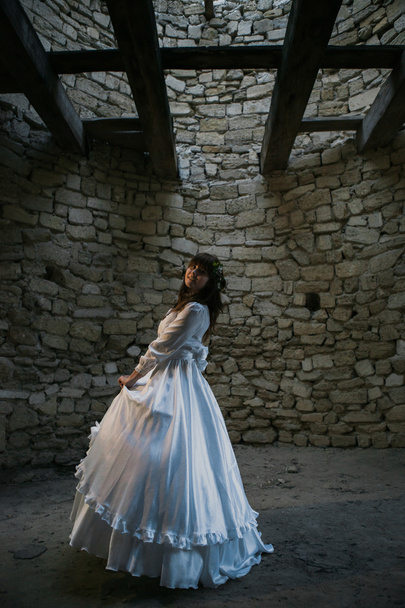Hermosa chica en vestido vintage blanco caminando cerca de la antigua casa de piedra. Concepto nupcial vintage
 - Foto, Imagen