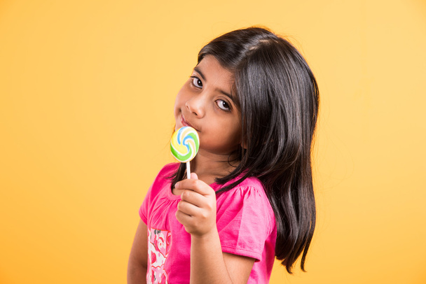 Ινδικό μικρό κορίτσι με Lolipop ή Loly pop, ασιατικό κορίτσι και Lolipop ή Lolipop, παιχνιδιάρικο Ινδικό χαριτωμένο κορίτσι που ποζάρει με Lolipop ή καραμέλα - Φωτογραφία, εικόνα