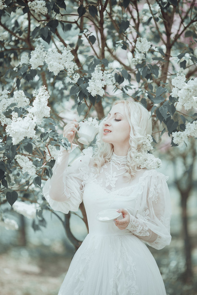 Beautiful blonde woman in blooming lilac garden. Vintage. Alice. - Фото, зображення