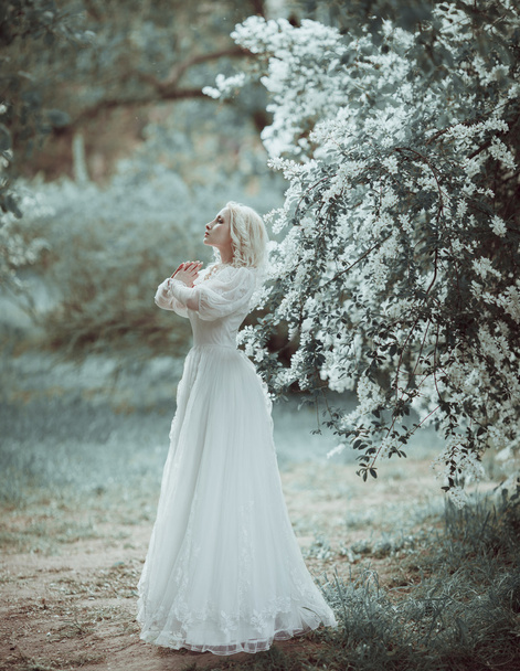 Beautiful blonde woman in blooming lilac garden. Vintage bride c - Fotó, kép
