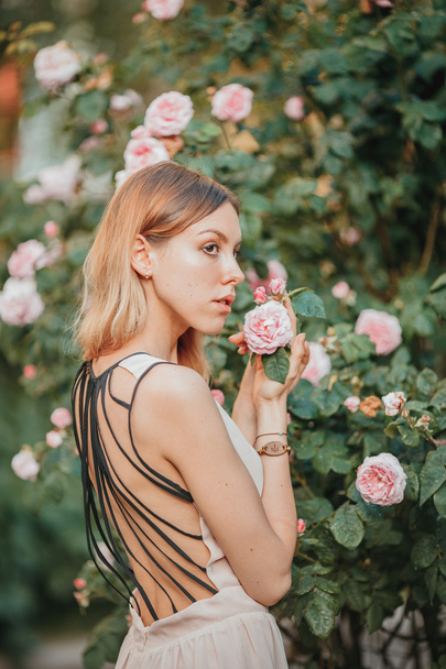Beautiful young girl in fashionable pink dress smelling roses. Fairytale. Fashion. Fantasy - Foto, Bild