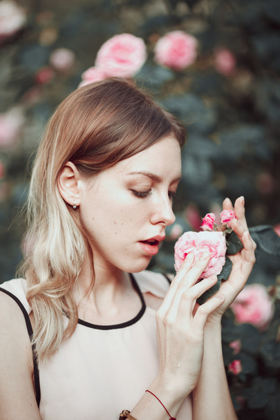 Beautiful young girl in fashionable pink dress smelling roses. Fairytale. Fashion. Fantasy - Valokuva, kuva
