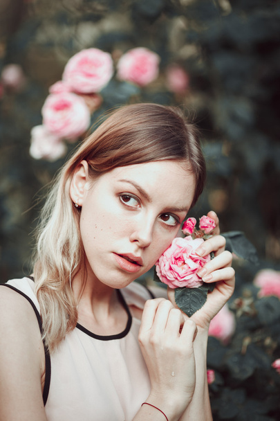 Beautiful young girl in fashionable pink dress smelling roses. Fairytale. Fashion. Fantasy - Valokuva, kuva