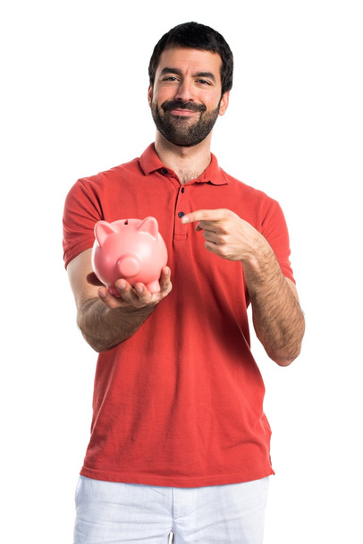 Handsome man holding a piggybank - Zdjęcie, obraz