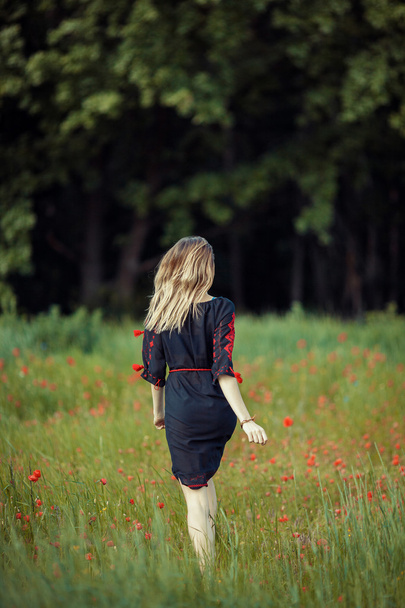 Beautiful ukrainian girl having fun in the poppy field. - Фото, зображення