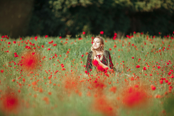 Beautiful ukrainian girl having fun in the poppy field. - Photo, Image