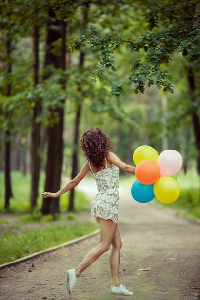 Szép fiatal lány szórakozás a nyári parkban színes lufik ünnepe. Boldog mosollyal ugrás koncepció - Fotó, kép