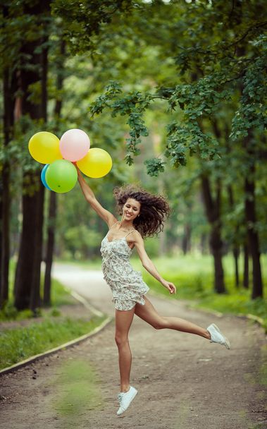 Krásná mladá dívka baví na letní park s barevnými balónky. Šťastný úsměv skok koncept - Fotografie, Obrázek