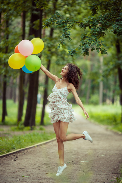 Krásná mladá dívka baví na letní park s barevnými balónky. Šťastný úsměv skok koncept - Fotografie, Obrázek