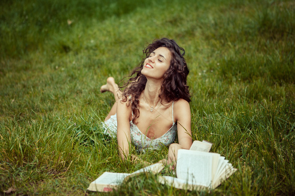 Beautiful young girl studying on green grass. Reading books - Foto, Imagen