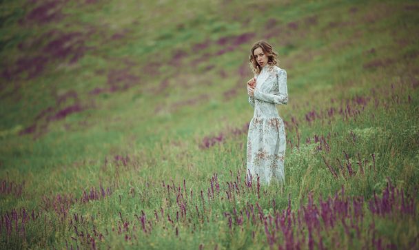 Mladá dívka v vintage šatech procházel sage flower pole. - Fotografie, Obrázek