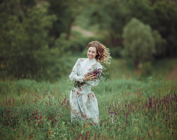 Young girl in vintage dress walking through sage flower field. - Fotoğraf, Görsel
