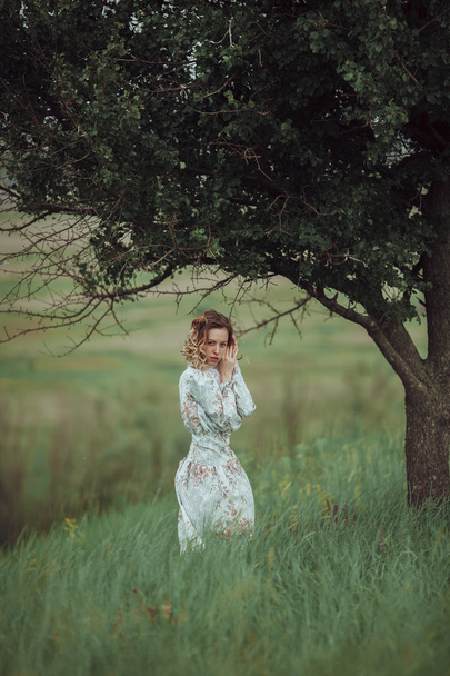 Young girl in vintage dress standing near lonely tree - Foto, Bild